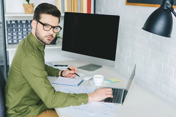 Libero professionista in occhiali che lavorano da computer portatile in ufficio leggero — Foto stock