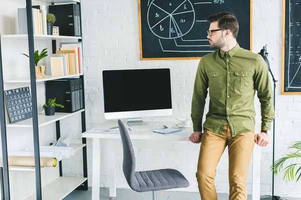 Homme d'affaires debout à table avec ordinateur au bureau à domicile — Photo de stock