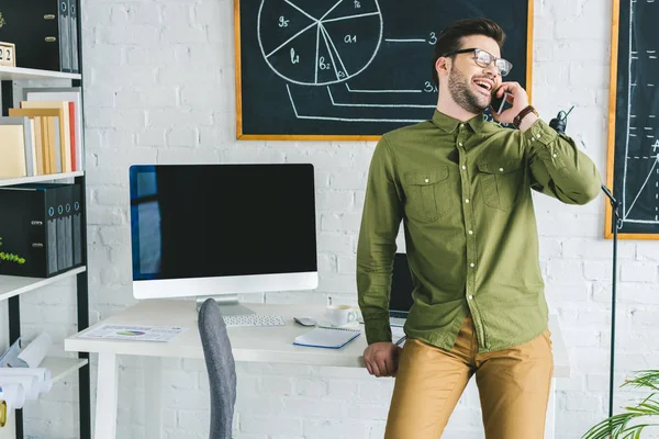 Laughing man talking on phone at home office — Stock Photo