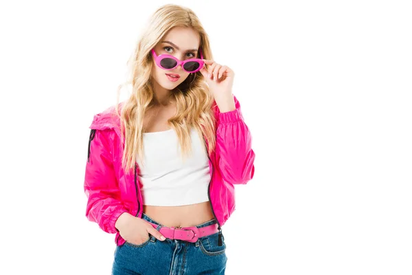 Attractive young woman dressed in pink touching sunglasses isolated on white — Stock Photo