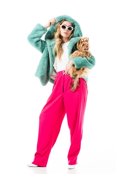 Chica joven con abrigo de piel sosteniendo lindo perro aislado en blanco - foto de stock