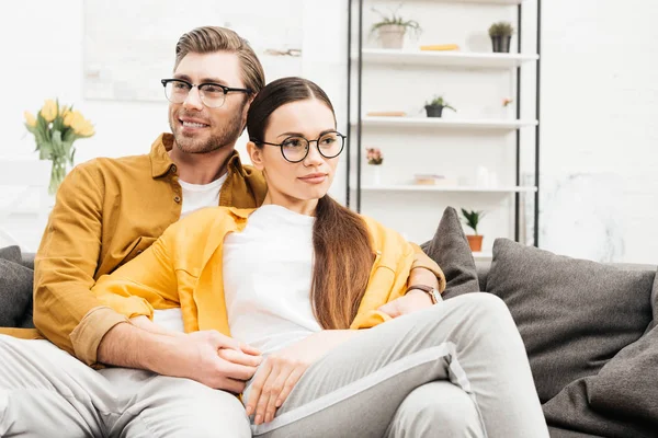 Joven feliz pareja relajarse en cómodo sofá en casa - foto de stock