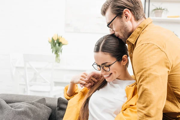 Hombre abrazando a su novia en el sofá en casa - foto de stock