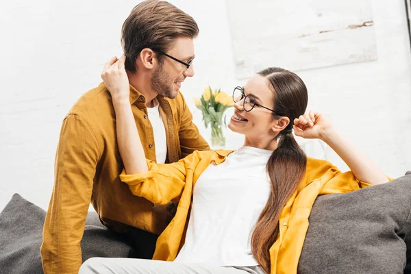 Feliz jovem casal flertando no sofá em casa — Fotografia de Stock