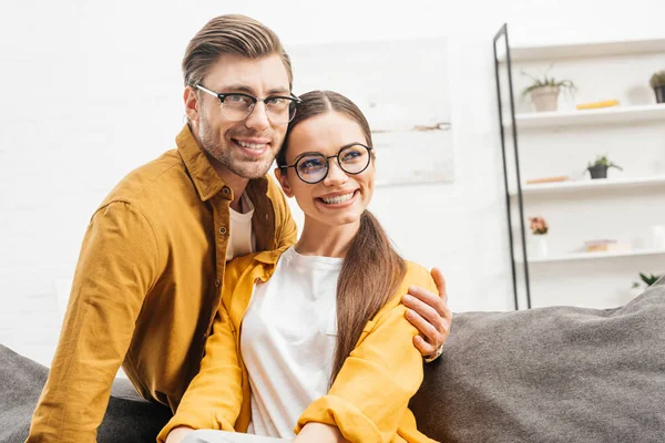 Happy young couple embracing on couch at home — Stock Photo