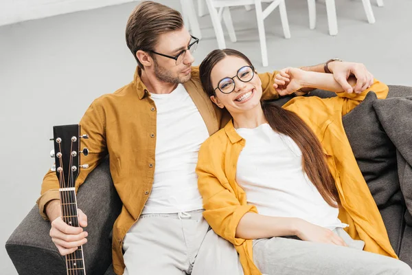 Blick aus der Vogelperspektive auf ein glückliches Paar mit Gitarre auf der heimischen Couch — Stockfoto