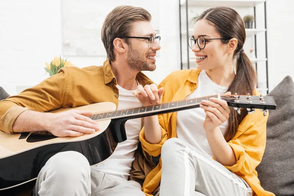 Sonriente joven tocando la guitarra para feliz novia - foto de stock