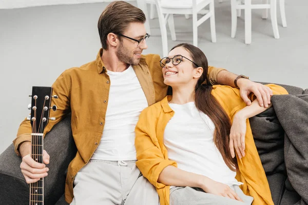 High angle view of couple with guitar sitting on couch at home — Stock Photo