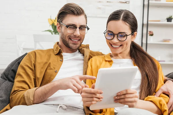 Couple heureux utilisant la tablette ensemble sur le canapé — Photo de stock