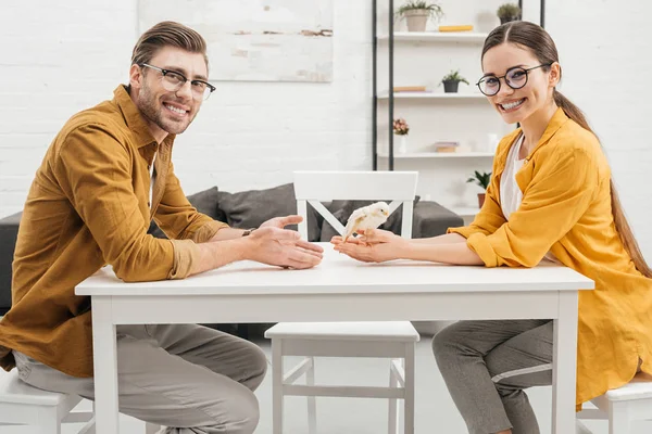 Young happy couple sitting with little chick on table — Stock Photo