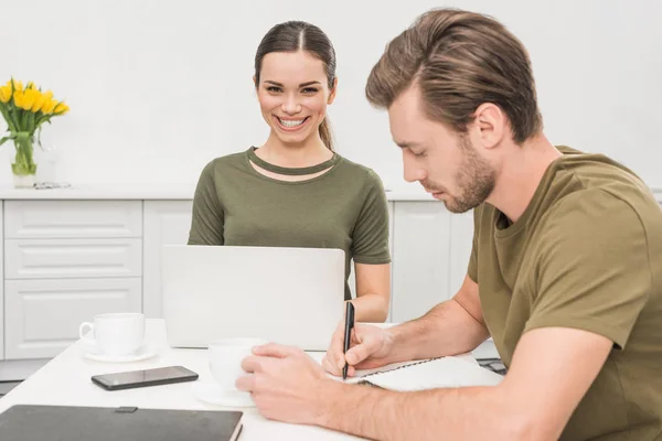 Pareja joven trabajando juntos en la cocina en casa - foto de stock