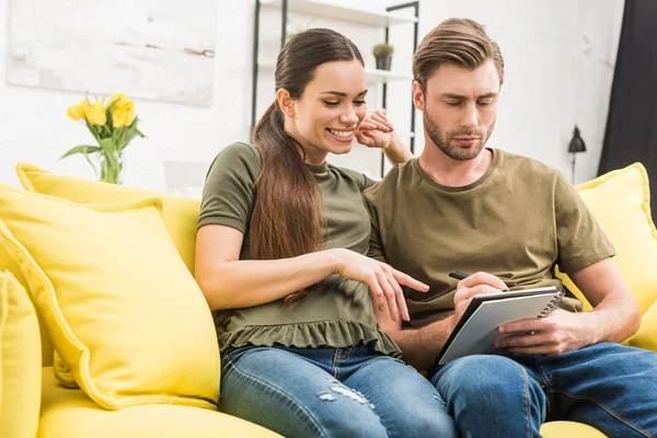 Pareja escribiendo en cuaderno juntos en acogedor sofá en casa - foto de stock