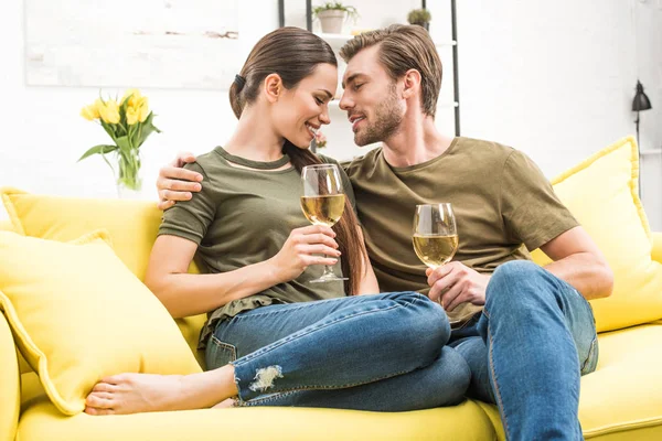 Jovem casal apaixonado beber vinho juntos no sofá em casa — Fotografia de Stock