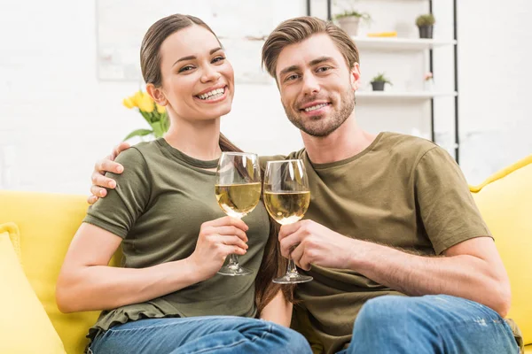 Пара чіпляється за келихи вина на дивані вдома — стокове фото
