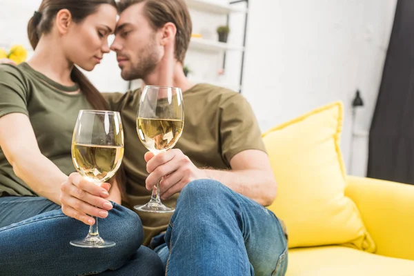 Abrazar pareja bebiendo vino juntos en el sofá en casa - foto de stock