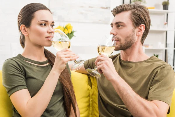 Jeune couple buvant du vin ensemble sur le canapé à la maison — Photo de stock