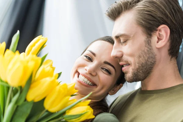 Gros plan de l'homme présentant des tulipes jaunes à sa petite amie heureuse — Photo de stock