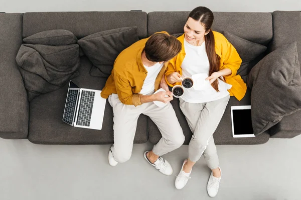 Vue du haut du couple boire du café ensemble sur un canapé confortable à la maison — Photo de stock