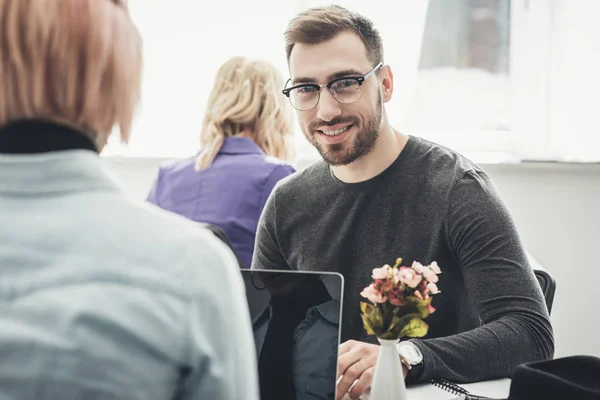 Selektiver Fokus eines lächelnden Geschäftsmannes mit Brille am Arbeitsplatz im Büro — Stockfoto