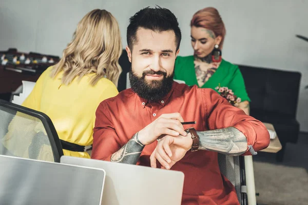 Enfoque selectivo del diseñador y los colegas que trabajan detrás en la oficina - foto de stock