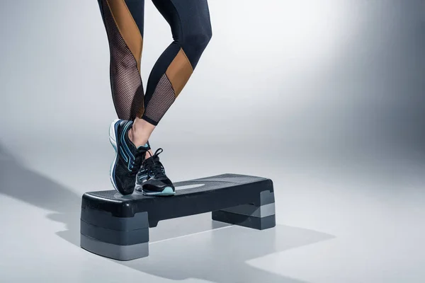 Close-up view of woman standing on step platform on grey background — Stock Photo