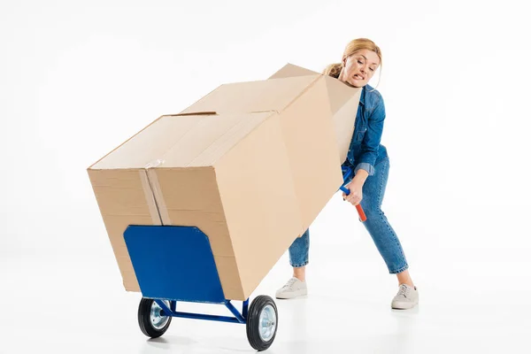 Attractive woman trying to push delivery cart with boxes isolated on white — Stock Photo