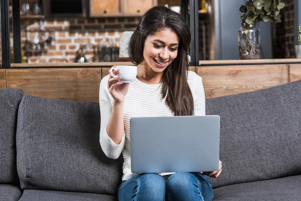 Menina americana africana feliz usando laptop e beber café no sofá — Fotografia de Stock