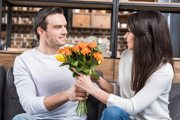 Coppia multietnica guardando l'un l'altro mentre l'uomo presenta mazzo di fiori alla donna — Foto stock