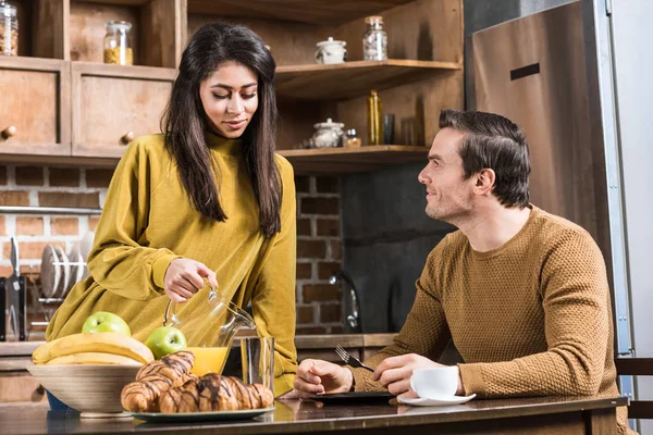 Young african american woman pouring juice to caucasian boyfriend — Stock Photo