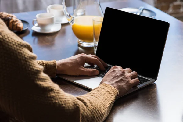 Cropped shot of man using laptop with blank screen during breakfast — Stock Photo