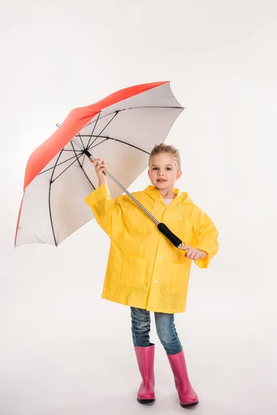 Niño preescolar en botas de goma, impermeable amarillo con paraguas, aislado en blanco - foto de stock