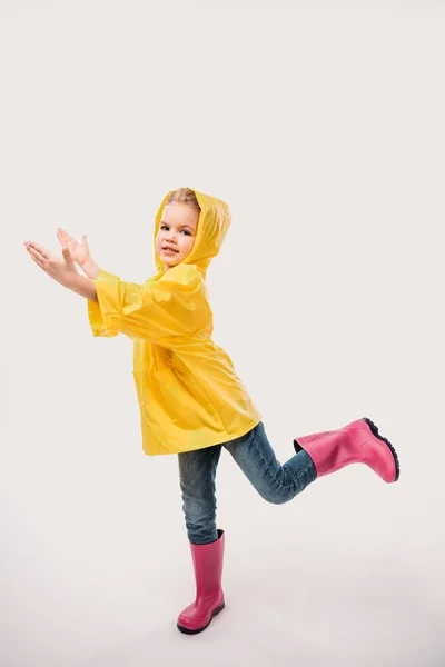 Schönes Kind in Gummistiefeln und gelbem Regenmantel, isoliert auf weiß — Stockfoto