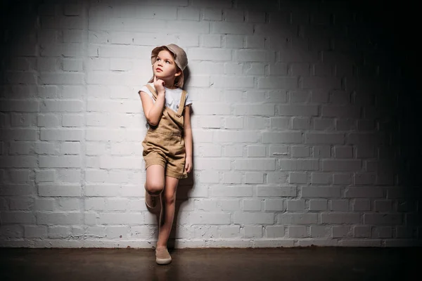 Thoughtful female child in safari costume standing at white wall — Stock Photo