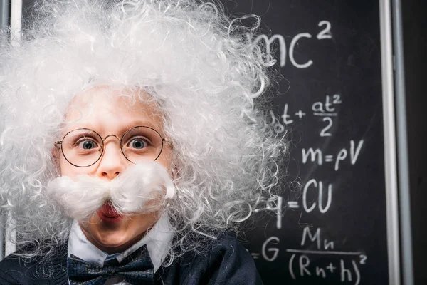 Little Einstein in eyeglasses with theory of relativity on chalkboard — Stock Photo