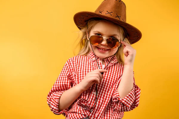 Stylish cowgirl in hat and sunglasses, isolated on yellow — Stock Photo