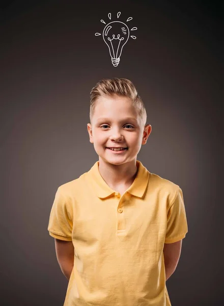 Adorable preteen smiling boy with drawn light bulb idea, isolated on grey — Stock Photo