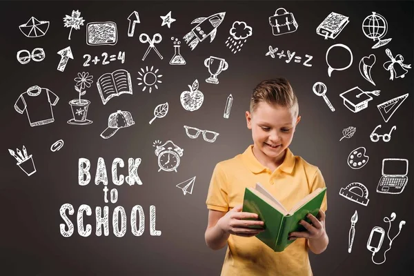 Preteen boy reading book, isolated on grey with educational icons and back to school lettering — Stock Photo