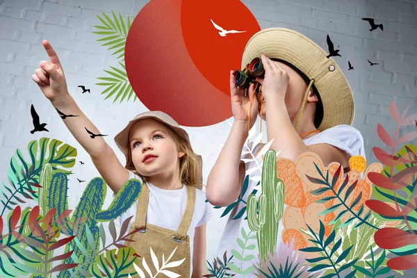 Niños en trajes de safari y sombreros apuntando y mirando con prismáticos a pájaros y cactus - foto de stock