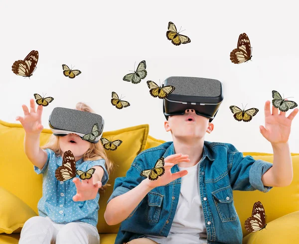 Схвильовані брати і сестри, використовуючи гарнітуру віртуальної реальності і дивлячись на метеликів — стокове фото