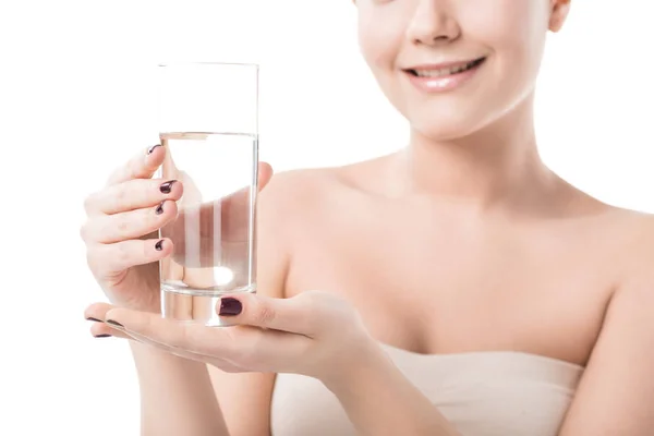 Обрізане зображення красивої усміхненої дівчини, що тримає склянку води ізольовано на білому — стокове фото