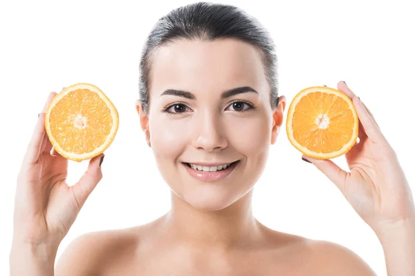 Sonrisa atractiva chica desnuda con la piel limpia sosteniendo mitades anaranjadas aisladas en blanco - foto de stock