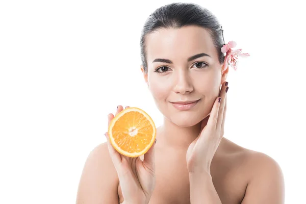 Attractive naked girl with clean skin holding orange and touching face isolated on white — Stock Photo