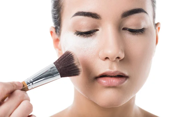 Image recadrée de visagiste faisant maquillage pour jeune femme avec de la poudre visage isolé sur blanc — Photo de stock