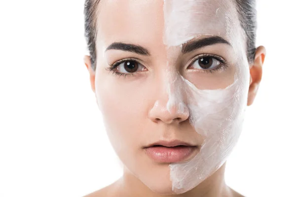 Hermosa chica con crema en la mitad de la cara mirando a la cámara aislada en blanco - foto de stock