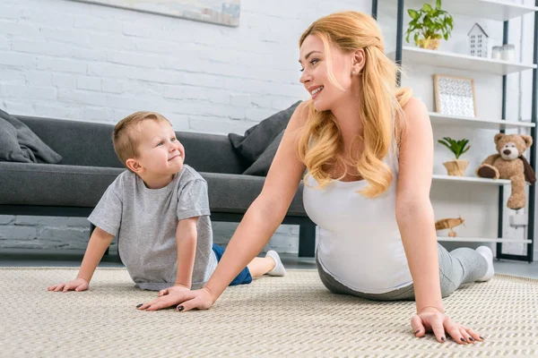 Feliz madre e hijo practicando yoga en la moderna sala de estar - foto de stock