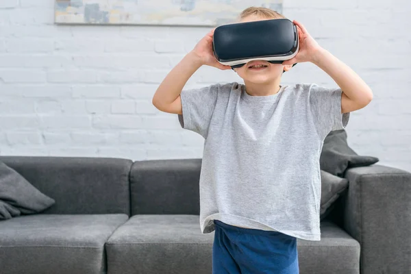 Little boy using virtual reality headset in front of sofa — Stock Photo