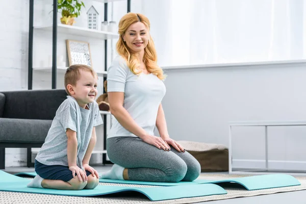 Усміхнений мати і син сидять на фітнес килимках — стокове фото