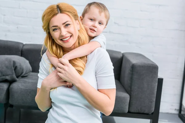 Kleiner Junge umarmt junge lächelnde Mutter — Stockfoto