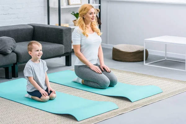 Smiling boy and mother resting on yoga mats — Stock Photo