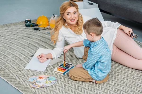 Smiling mother and little son with paintbrushes — Stock Photo